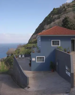 a blue house on the side of a hill at Casa Azul - Ocean View in Porto Moniz