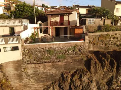 a house on top of a cliff with a mountain at Madeira Black Sand House by Stay Madeira Island in Seixal