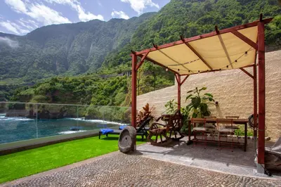 a patio with a table and a view of a mountain at Madeira Black Sand House by Stay Madeira Island in Seixal