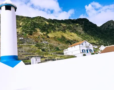 a white lighthouse with a mountain in the background at Alo Baía São Lourenço in Santa Bárbara