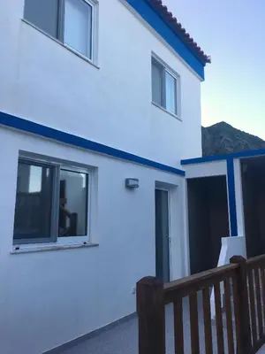 a white house with a blue stripe on it at Alo Baía São Lourenço in Santa Bárbara