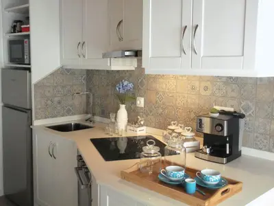 a kitchen with white cabinets and a wooden tray with cups at Alo Baía São Lourenço in Santa Bárbara