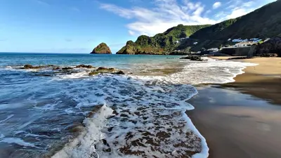 a beach with rocks and the ocean and mountains at Alo Baía São Lourenço in Santa Bárbara