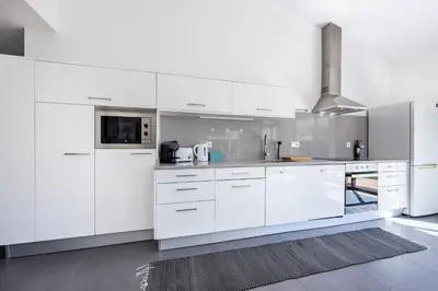 a white kitchen with white cabinets and appliances at Villa Botelha in Sagres
