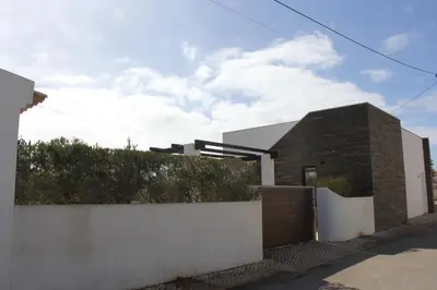 a house with a brick wall next to a fence at Villa Botelha in Sagres