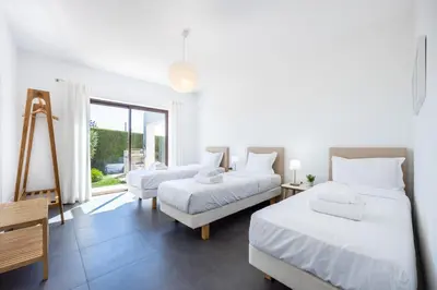 a white room with two beds and a window at Villa Botelha in Sagres