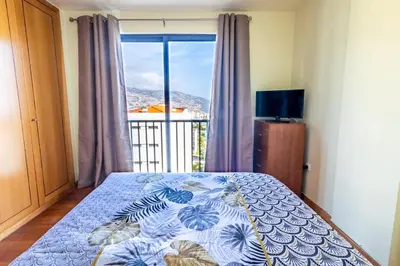 a bedroom with a bed and a large window at LULINA Two Bedroom by ALMA Holiday Rentals in Funchal