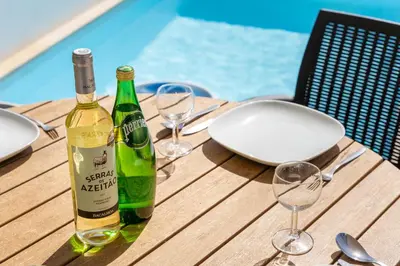 a bottle of wine sitting on a wooden table with glasses at Villa Hobie Cat in Sagres
