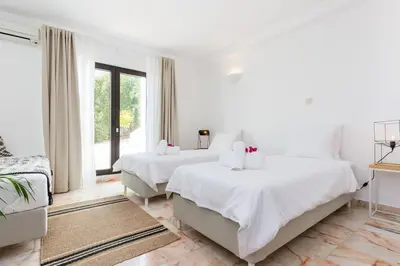 a white bedroom with two beds and a couch at Ocean view beach villa in Budens