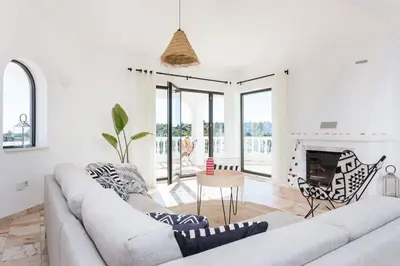 a white living room with a couch and a fireplace at Ocean view beach villa in Budens