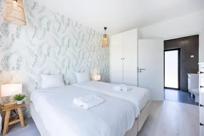 a bedroom with a large white bed with towels on it at Villa Front Loop in Sagres