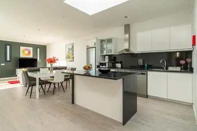 a kitchen with white cabinets and a table with chairs at OurMadeira - Sunset Cliff Villas in Fajã da Ovelha