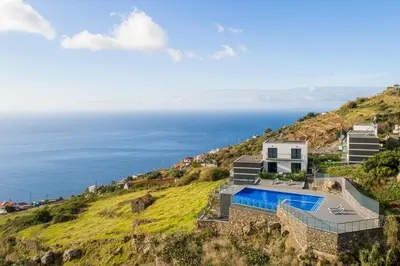an aerial view of a house on a hill with the ocean at OurMadeira - Sunset Cliff Villas in Fajã da Ovelha