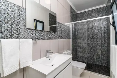 a white bathroom with a sink and a shower at OurMadeira - Sunset Cliff Villas in Fajã da Ovelha