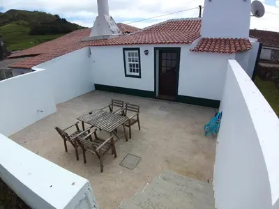 a patio with a table and chairs in front of a white house at Casa Malbusca in Almagrinha