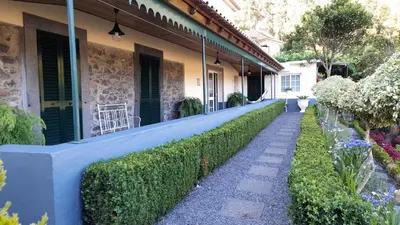 a house with a blue wall and a hedge at Quintinha da Romana in Câmara de Lobos