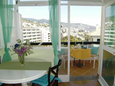 a table with a vase of flowers on a balcony at Bright Studio in Funchal