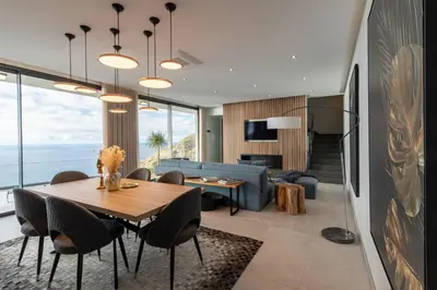a living room with a table and a blue couch at The Cliffhouse by LovelyStay in Fajã da Ovelha