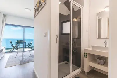 a bathroom with a shower and a sink with a view of the ocean at Belle Vue Résidence by Atlantic Holiday in Santa Cruz