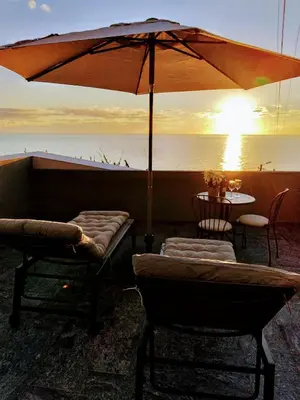 a patio with a table and an umbrella and chairs at Anjos's Choice in Ponta do Sol