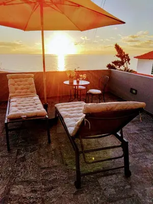 a balcony with an umbrella and a table and chairs at Anjos's Choice in Ponta do Sol