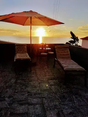 a patio with two chairs and an umbrella and a table at Anjos's Choice in Ponta do Sol