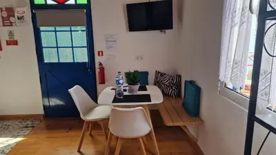 a living room with a bed and two chairs and a table at Casa Villa Dinastía Sótão Y Casa Villa Dinastía Miramar in Ribeira Brava