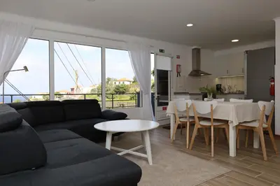 a living room with a couch and a table and a kitchen at Casa das Feiteiras by AnaLodges in Ponta Delgada