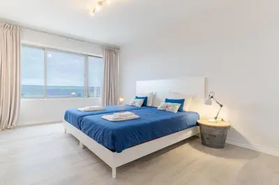 a bedroom with a blue bed and a large window at top floor arriaga apartment 804 in Funchal