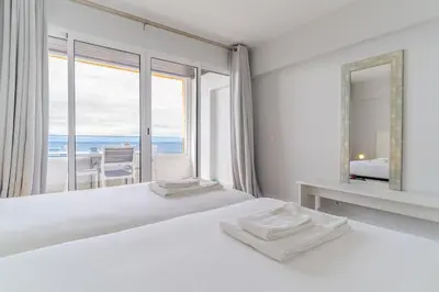 a white bedroom with a view of the ocean at top floor arriaga apartment 804 in Funchal