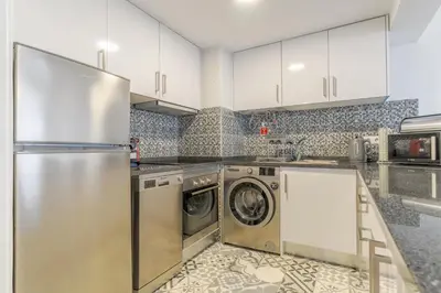 a kitchen with white cabinets and a washer and dryer at top floor arriaga apartment 804 in Funchal