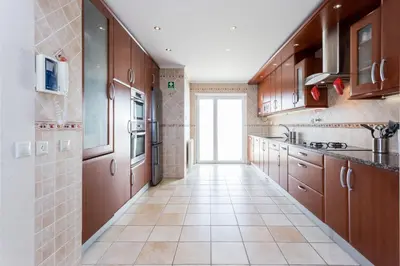 a kitchen with wooden cabinets and a tile floor at CoolHouses Algarve Luz, Ocean front 4 Bed house w/ pool, Casa da Pipa in Luz