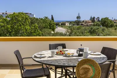 a table with food and drinks on a balcony with palm trees at CoolHouses Algarve Luz, 2 Bed semi detached villa, Jardim das Palmeiras condominium, Villa A in Montinhos da Luz