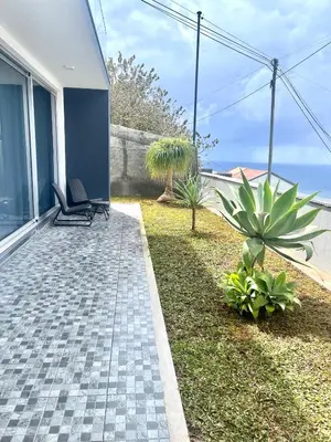 a patio with two chairs and plants next to a house at Villa Cassolino in Ribeira Brava
