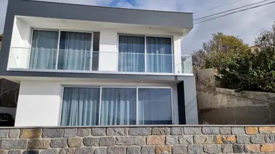 a white house with windows and a stone wall at Villa Cassolino in Ribeira Brava