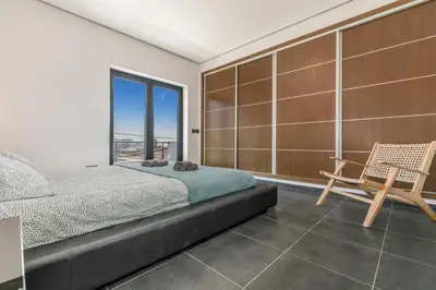 a bedroom with a bed and a chair and a window at Casa Amizade in Aljezur