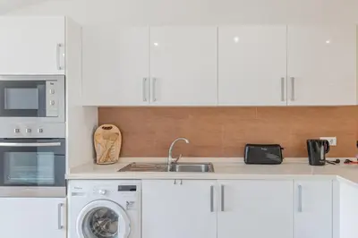 a kitchen with white cabinets and a sink and a dishwasher at Centre Funchal top floor terrace & large balconies in Funchal