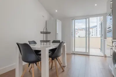 a dining room with a white table and black chairs at Centre Funchal top floor terrace & large balconies in Funchal