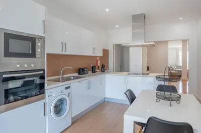 a kitchen with white cabinets and a sink and a dishwasher at Centre Funchal top floor terrace & large balconies in Funchal