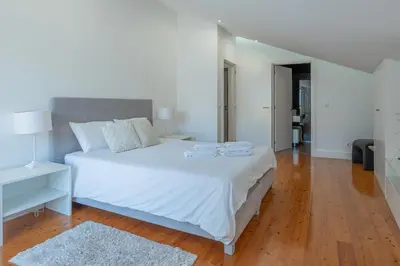 a bedroom with a white bed and a wooden floor at Centre Funchal top floor terrace & large balconies in Funchal