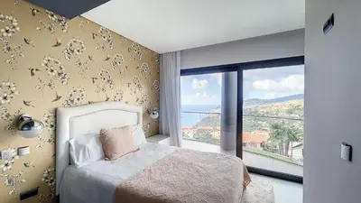 a bedroom with a bed and a large window at Villa Bonsai in Arco da Calheta