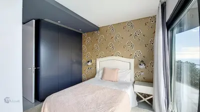 a bedroom with a bed and a wall with floral wallpaper at Villa Bonsai in Arco da Calheta