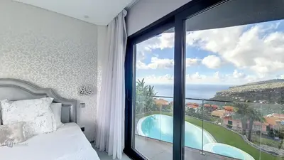 a bedroom with a bed and a large window at Villa Bonsai in Arco da Calheta