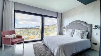a bedroom with a bed and a large window at Villa Bonsai in Arco da Calheta