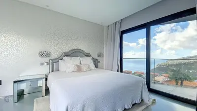 a bedroom with a bed and a large window at Villa Bonsai in Arco da Calheta