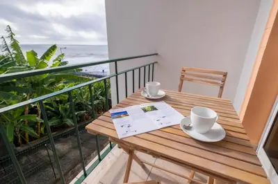 a wooden table on a balcony with a view of the ocean at Sol&mar in Ponta do Sol