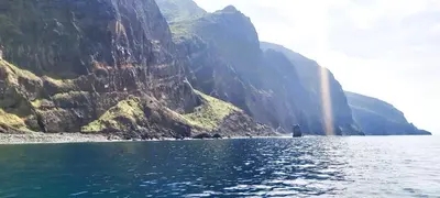 a person standing in the water next to a mountain at Apartamento do Corpo Santo in Funchal