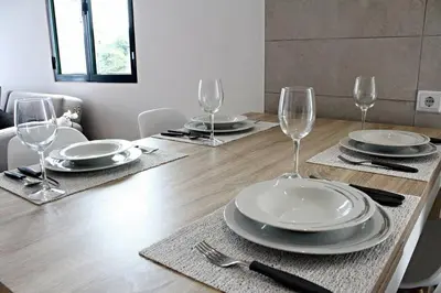 a wooden table with plates and wine glasses on it at Pedreira apartment in Calheta