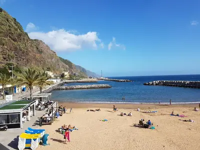 a group of people on a beach near the ocean at Pedreira apartment in Calheta
