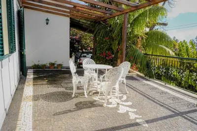 a patio with white chairs and a table at Granny's house view in Funchal